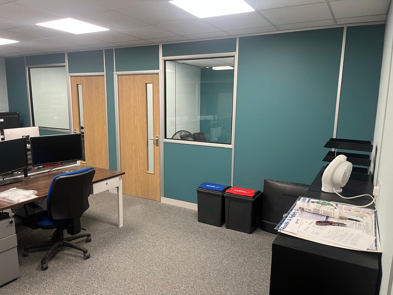 A finished office with teal partition walls, glazed panels and oak doors