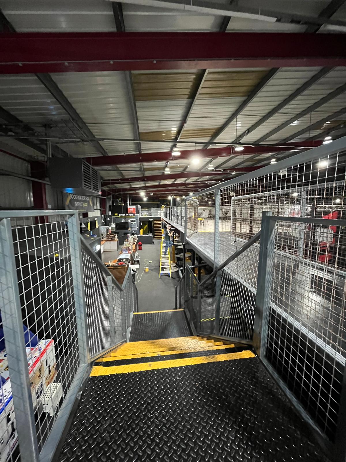 Mezzanine walkway with mesh infill panels and chequer-plate stairs in a leisure venue